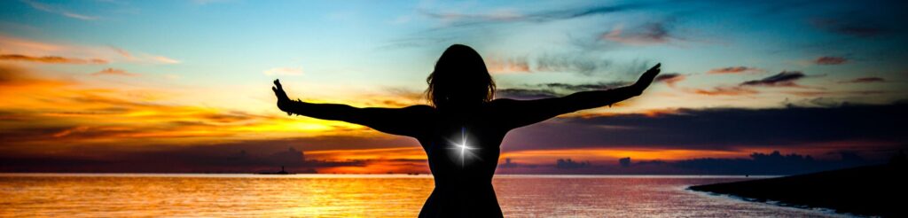 Goddess with glowing orb of light in her chest, standing in an open stance with calm waters in the background, symbolizing emotional healing and transformation.